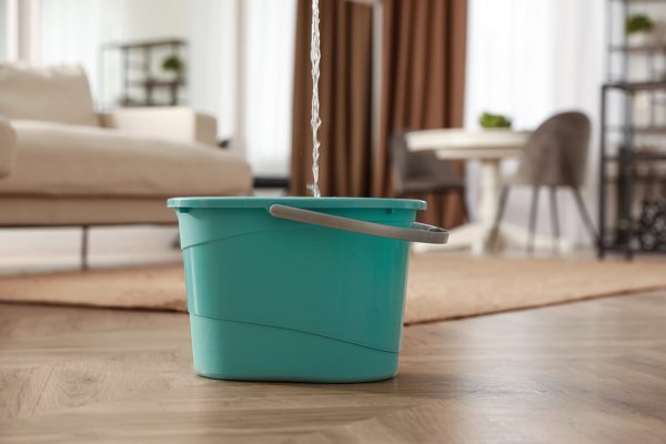 a green bucket catching water from the leaking roof