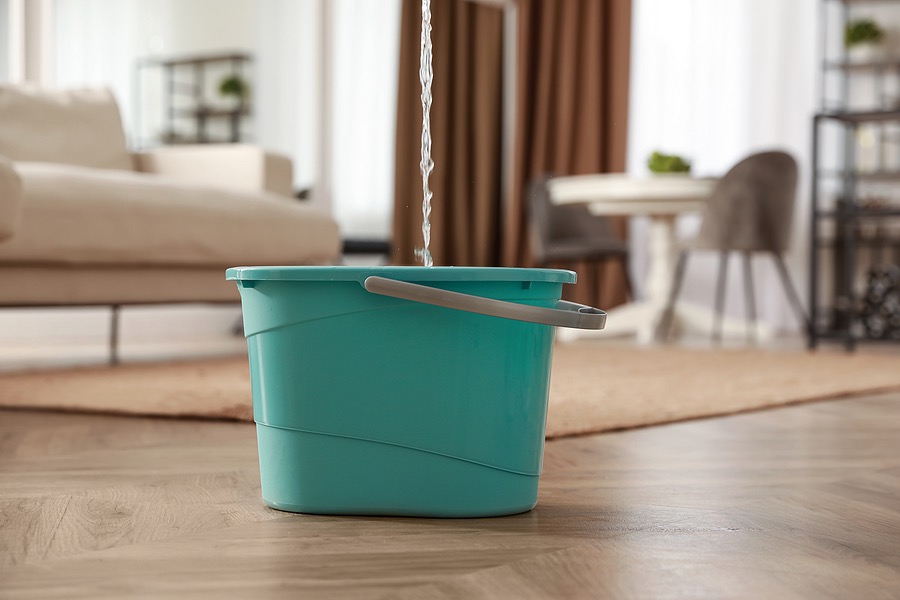 a green bucket catching water from the leaking roof